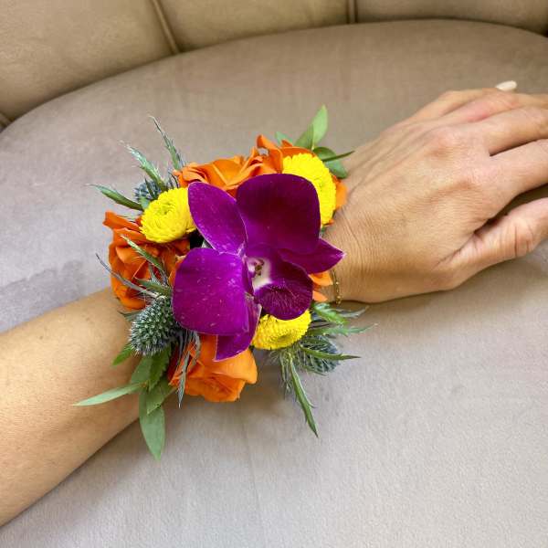 Wrist corsage with purple orchid, orange roses, and yellow blooms