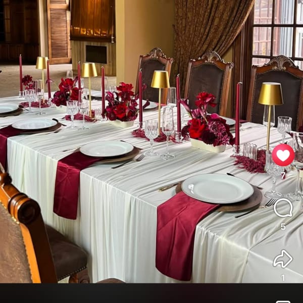 Wedding reception table with red floral centerpieces and gold candle holders