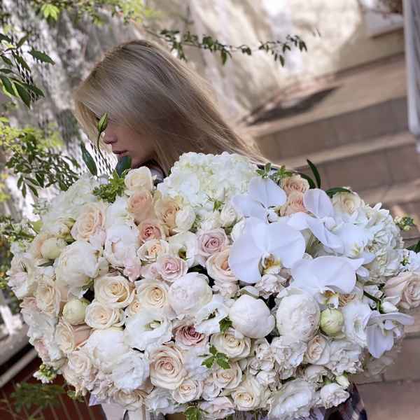 Woman holding a large bouquet of white and blush flowers in a box