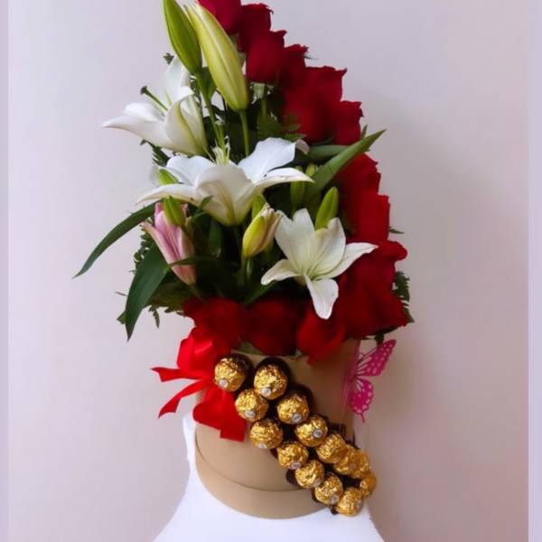 Red and white lily arrangement with gold chocolates on a hat box