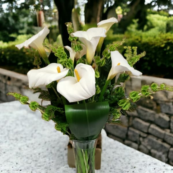 White calla lilies arranged in a clear glass vase