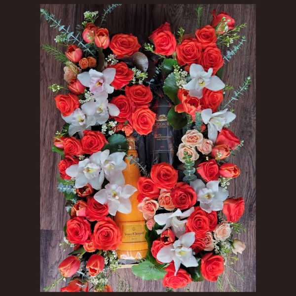 Red roses and white orchids arranged around a champagne bottle