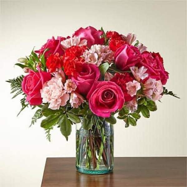 Pink roses and carnations in a clear glass vase