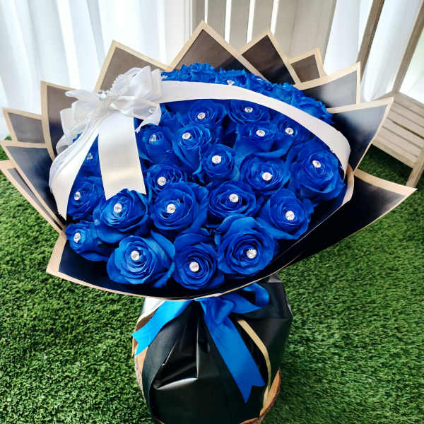 Bouquet of bright blue roses wrapped in black paper with a white ribbon