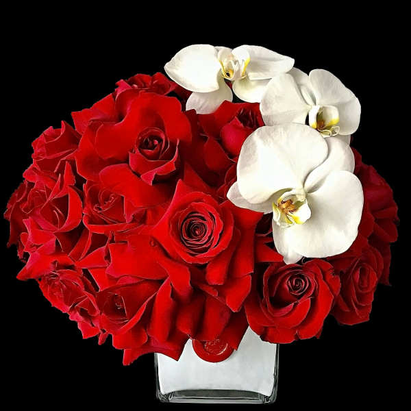 Red roses with white orchids in a clear square vase