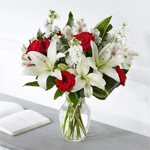 Red roses and white lilies arranged in a clear glass vase