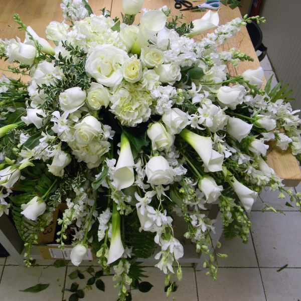 Large white floral arrangement with roses, calla lilies, and orchids