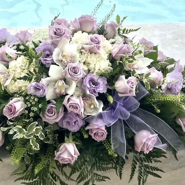 Lavender roses and white orchids arranged with a purple ribbon.