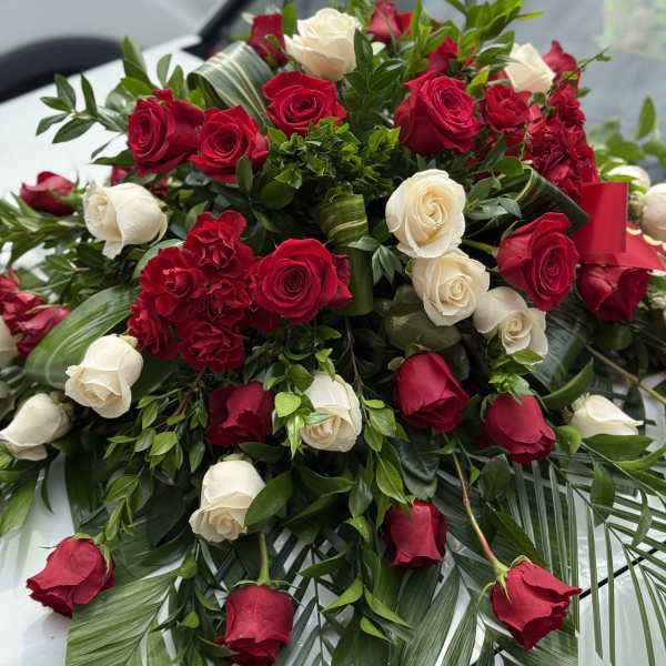 Red and white roses arranged with greenery and palm fronds