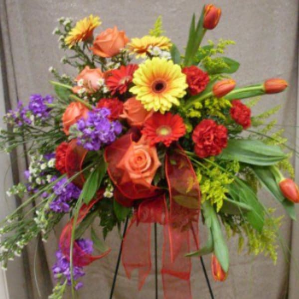 Colorful standing floral arrangement with roses, gerbera daisies, tulips, and ribbon