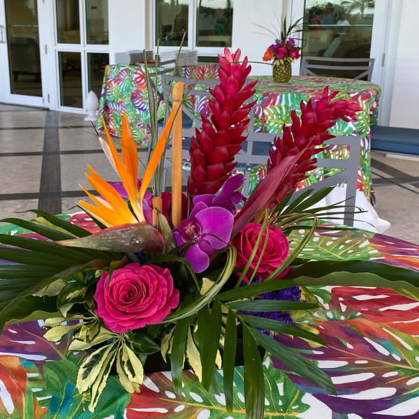 Tropical floral centerpiece with pink roses, purple orchids, and red ginger flowers
