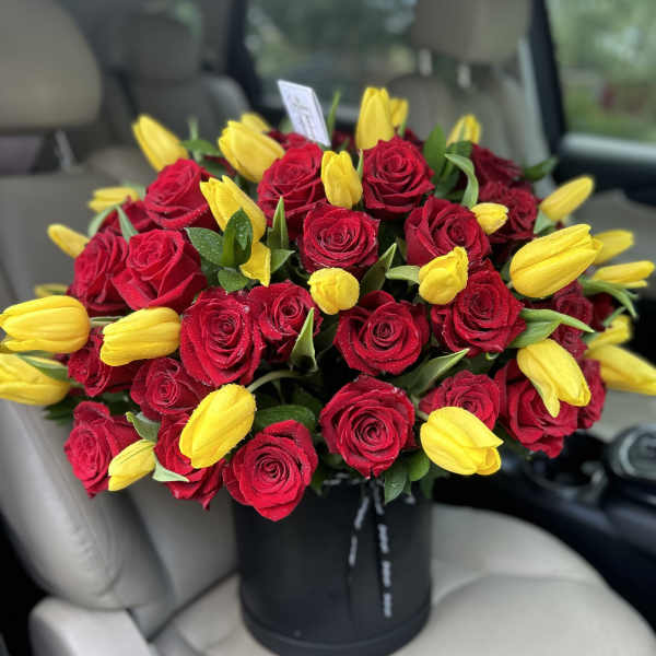 Bouquet of red roses and yellow tulips in a black hat box