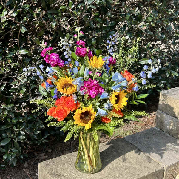 Bright mixed bouquet in a clear glass vase with sunflowers and roses