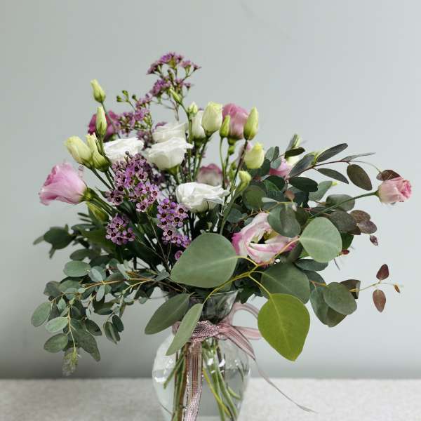 Pink and white bouquet in a clear glass vase with eucalyptus