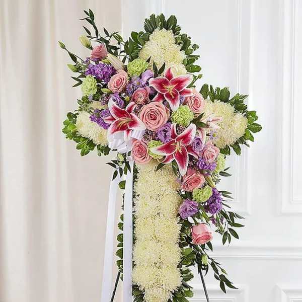 Standing floral cross with pink roses and lilies on a white easel