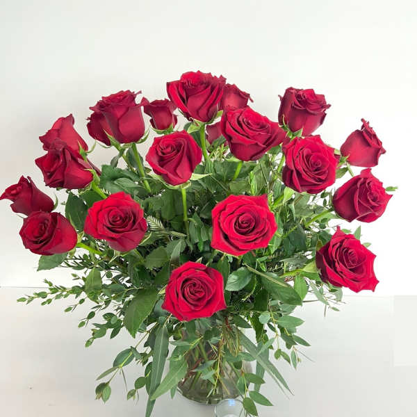 Bouquet of red roses in a clear glass vase with a small candle nearby