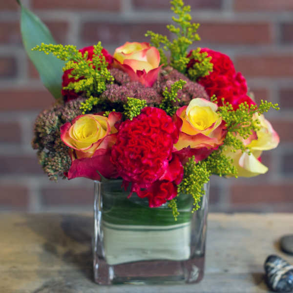 Bouquet of red and yellow roses in a square glass vase