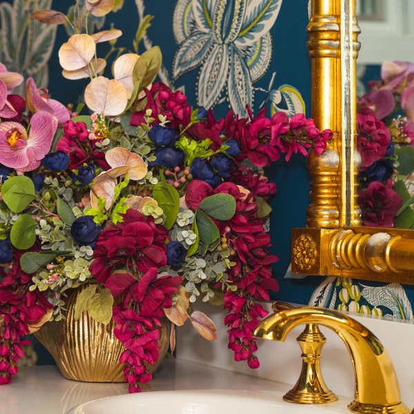 Pink orchids and magenta flowers arranged in a gold vase