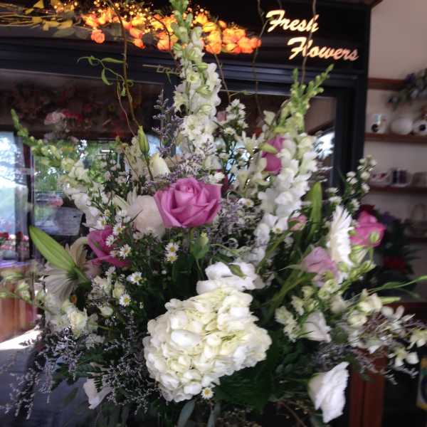 Tall mixed bouquet with pink roses and white blooms in a glass vase