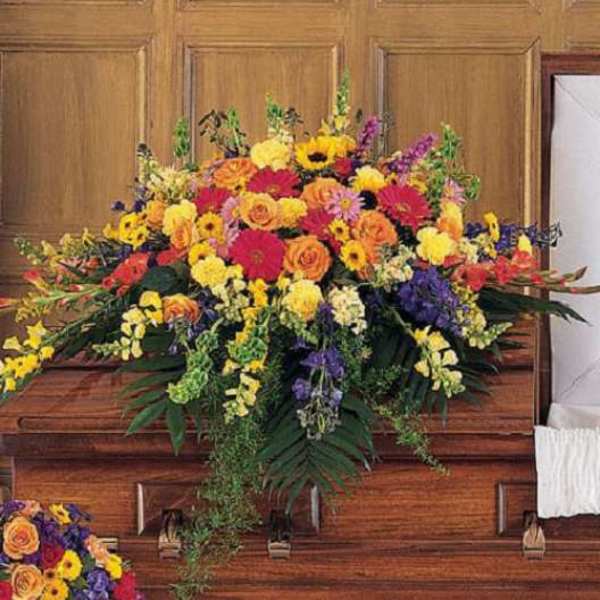 Large colorful flower spray on a wooden casket