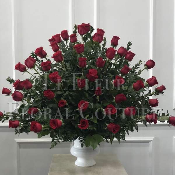 Large arrangement of red roses in a white pedestal vase