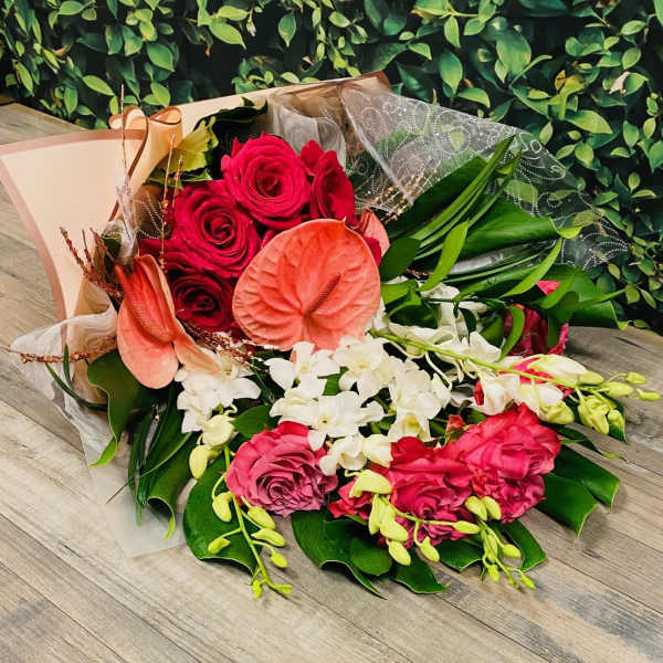 Bouquet of red roses, pink anthuriums, and white orchids with green leaves