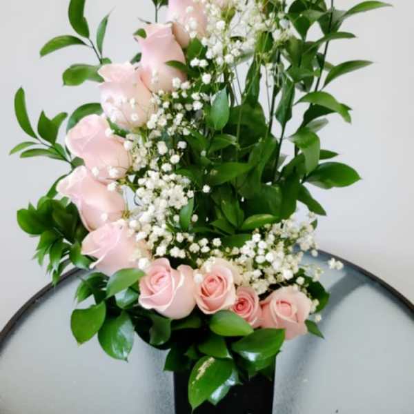 Pink roses with baby's breath in a black vase