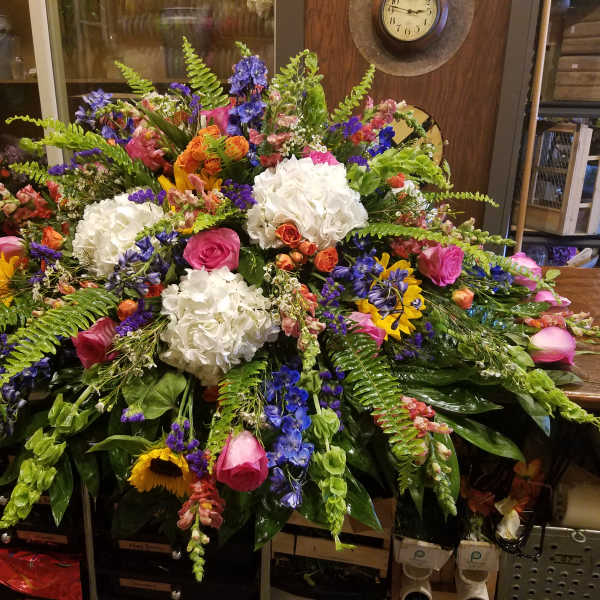 Large mixed floral arrangement with white hydrangeas, pink roses, and blue flowers