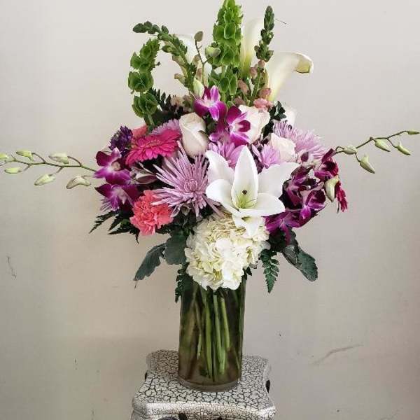Tall mixed bouquet in a glass vase with white lilies and purple flowers