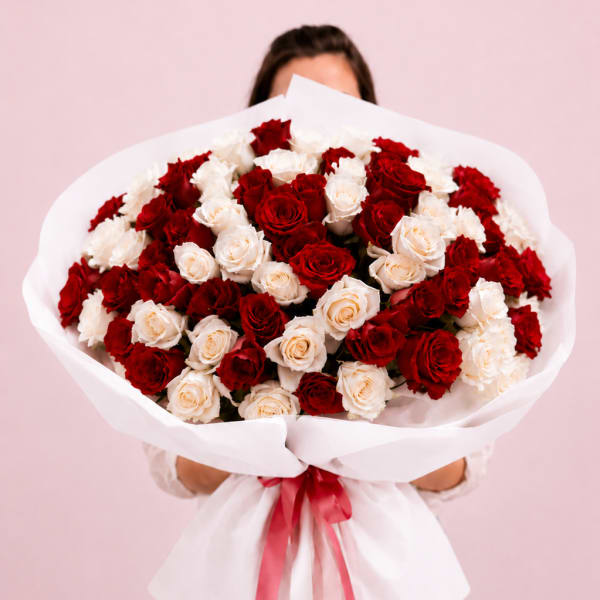Large bouquet of red and white roses wrapped in white paper with a red ribbon