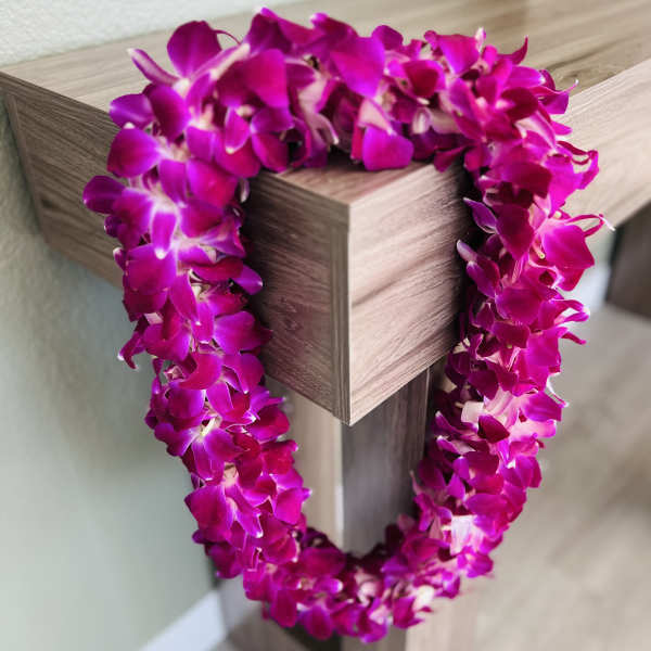 Magenta orchid lei draped over a wooden post