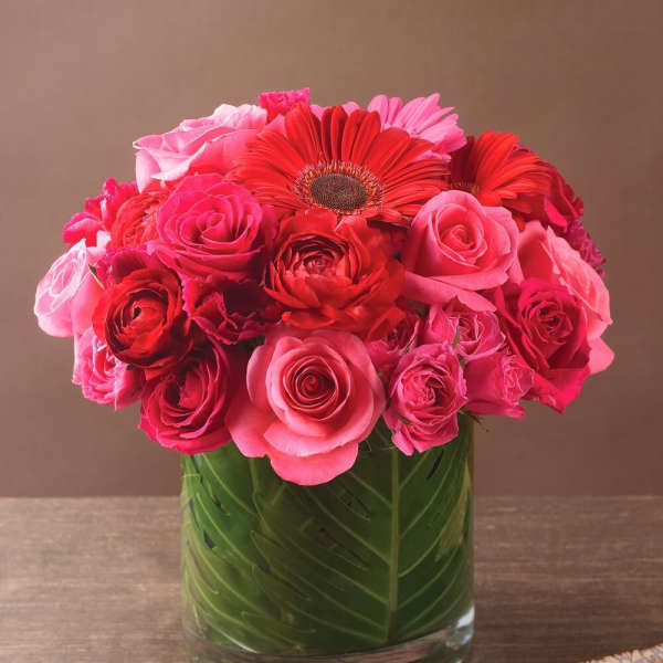 Pink and red roses with gerbera daisies in a glass vase