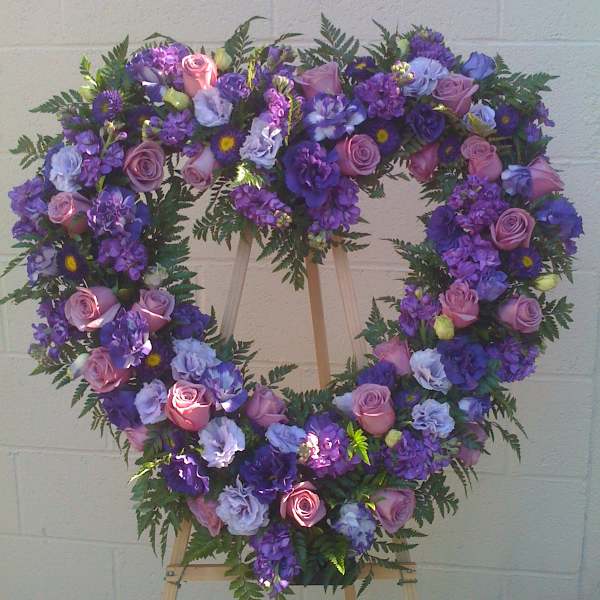 Heart-shaped floral wreath with pink and purple flowers on an easel