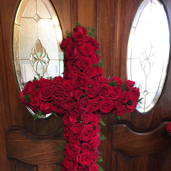 Cross-shaped arrangement of red roses on a stand