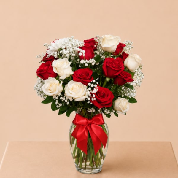 Red and white roses in a glass vase with a red ribbon