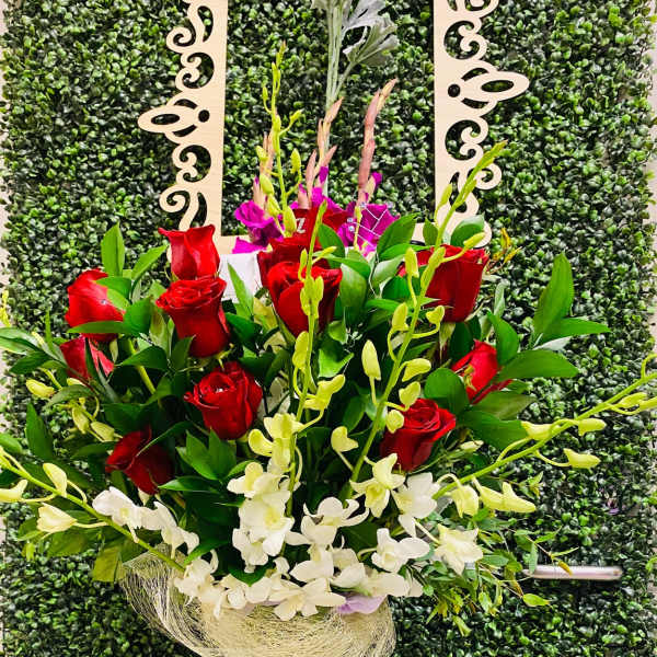 Tall bouquet of red roses and white orchids in a clear glass vase