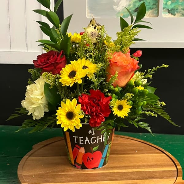 Colorful mixed flower arrangement in a teacher-themed pot