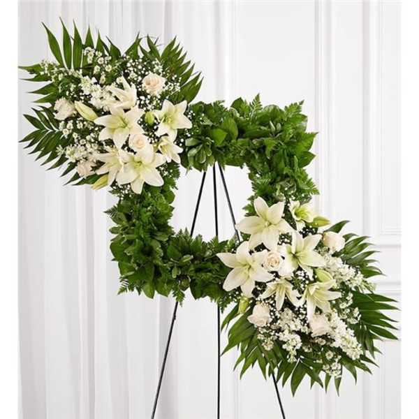 White floral funeral wreath on a black stand