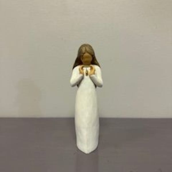 Small angel figurine in a white dress holding a gold heart