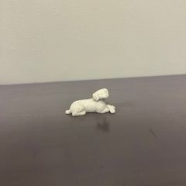 Small white plush dog lying on a dark surface