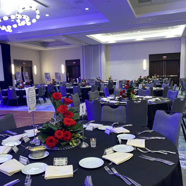 Round banquet tables with red rose centerpieces in a reception hall
