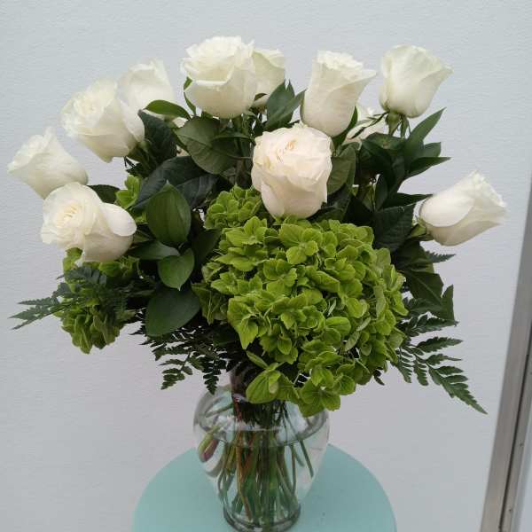 White roses and green hydrangeas in a clear glass vase