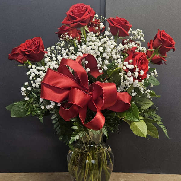 Red roses with baby's breath in a glass vase and red ribbon