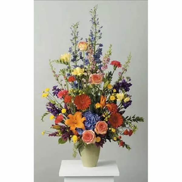 Tall mixed bouquet in a pale green vase with multicolored blooms
