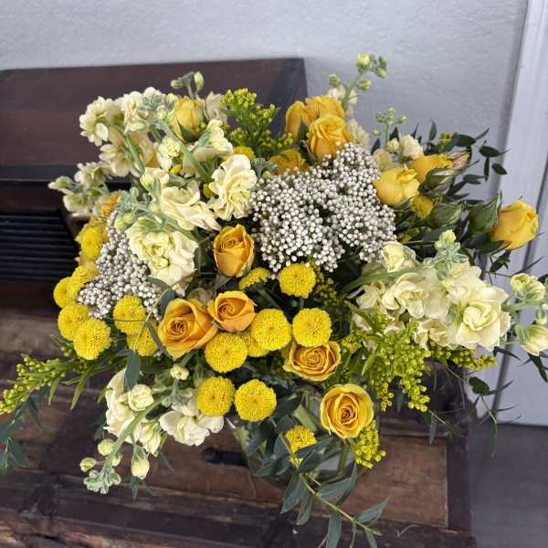 Yellow roses and cream flowers arranged in a bouquet
