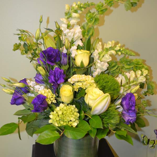 Purple and yellow floral arrangement in a glass vase