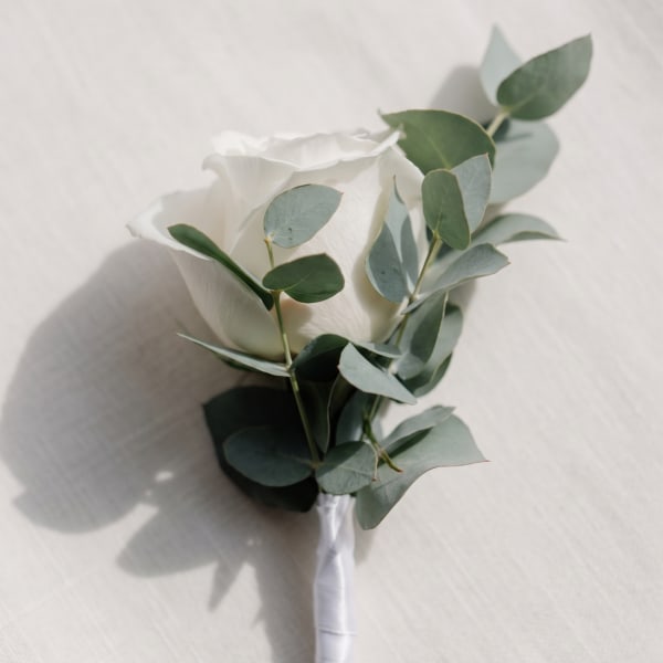 White rose boutonniere with eucalyptus leaves and a wrapped stem