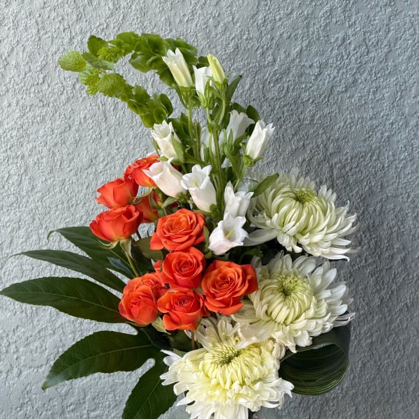 Orange roses and white chrysanthemums in a glass vase