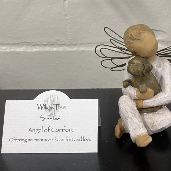 Decorative angel figurine holding a small dog with a Willow Tree card beside it