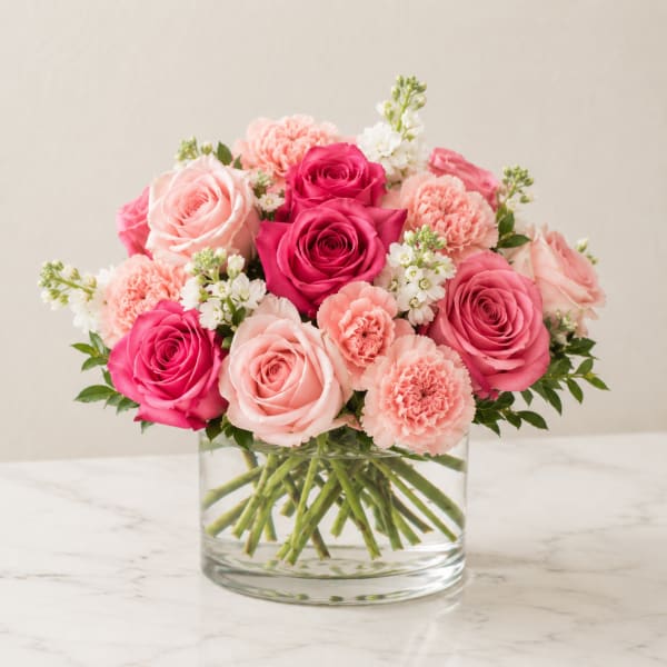 Pink and peach roses with carnations in a clear glass vase